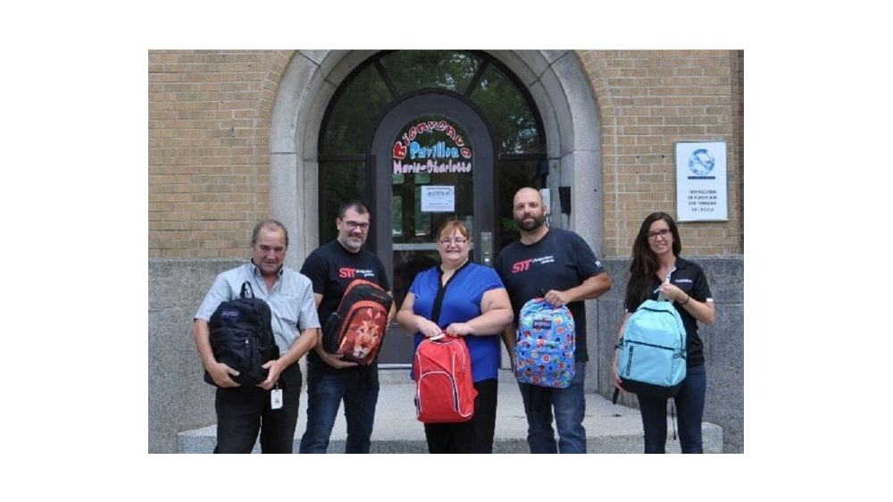 Bridgestone Americas Joliette Canada employees holding backpacks for kids